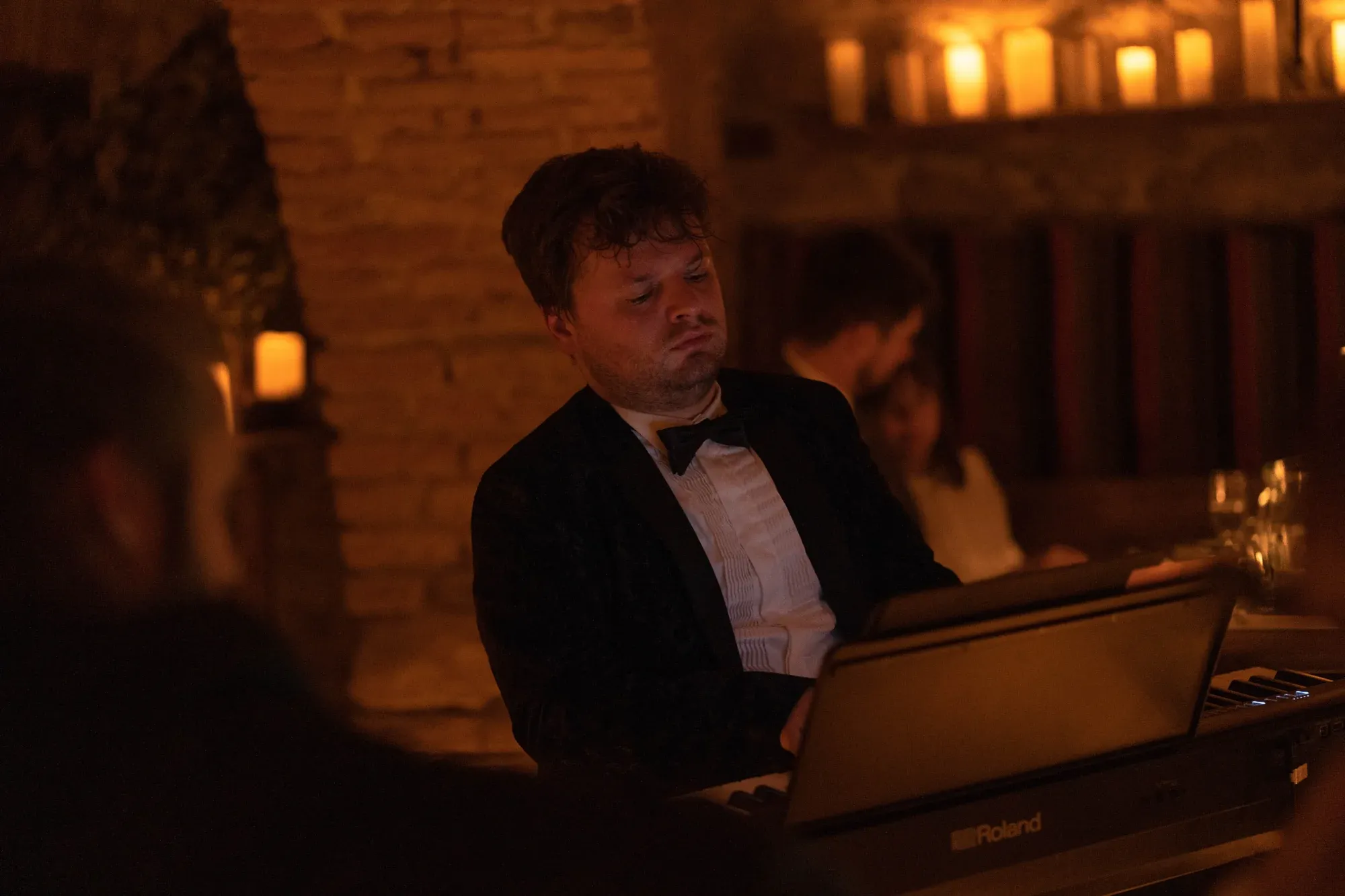 A pianist performing in front of the candlelit stone walls of the castle wine cellar