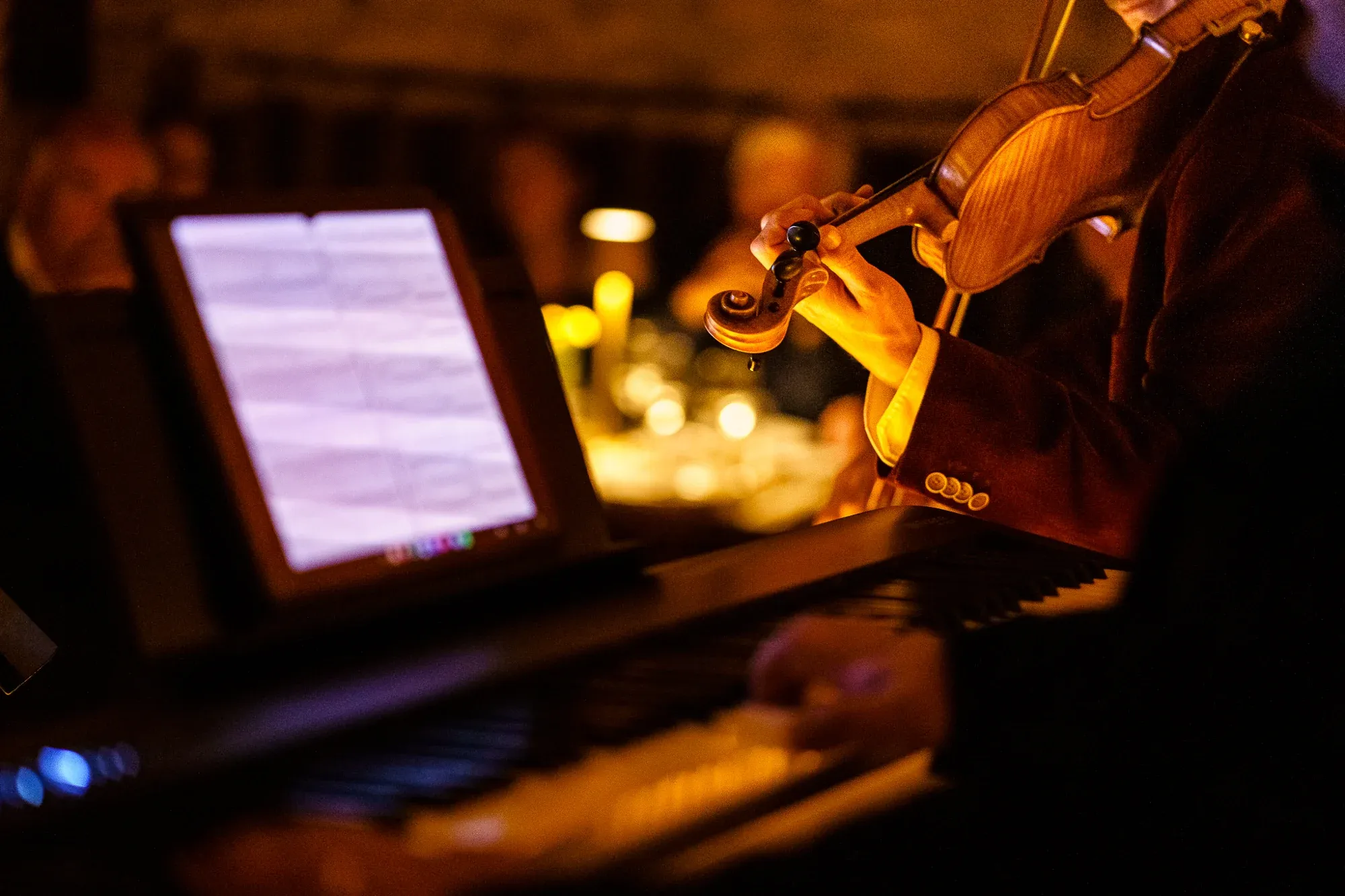 A close view of a violin, bow and musical score during a candlelit performance