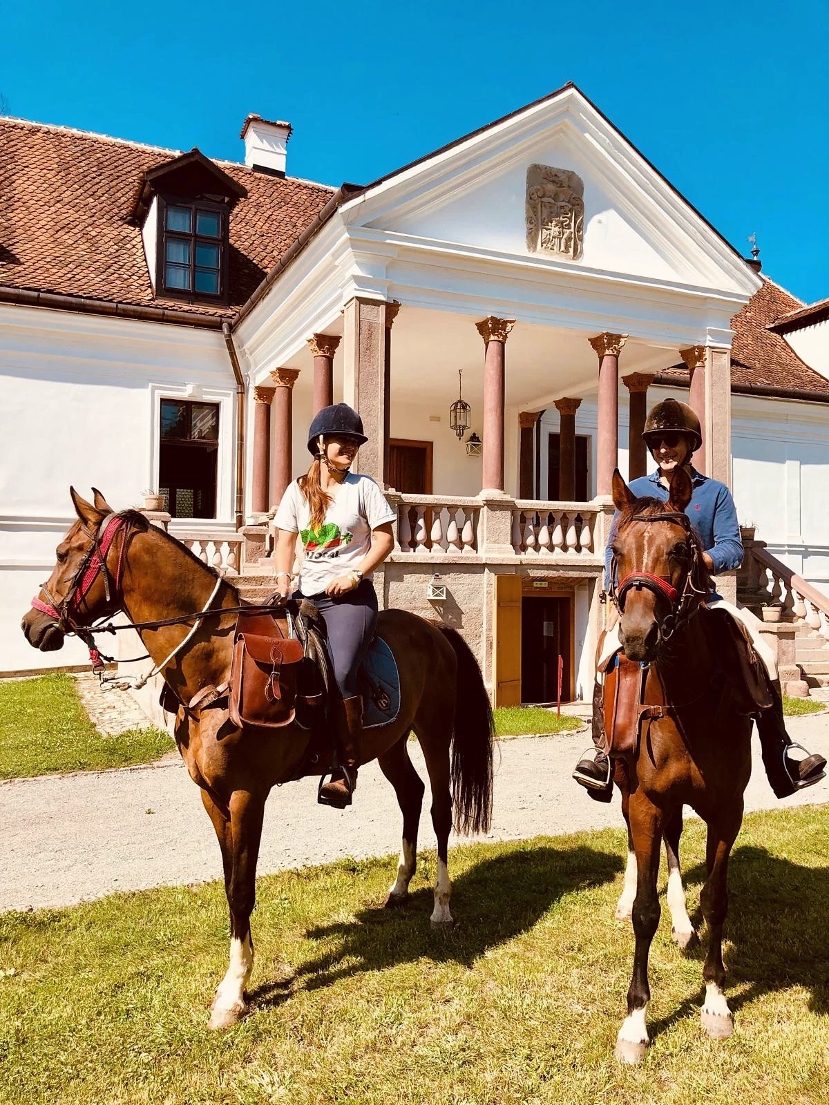 Two riders on horseback in front of Kálnoky Castle