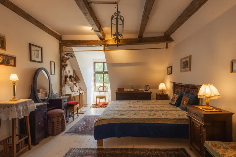 The Bride’s Room inside Miklósvár Castle, with exposed beams and a blue-covered double bed
