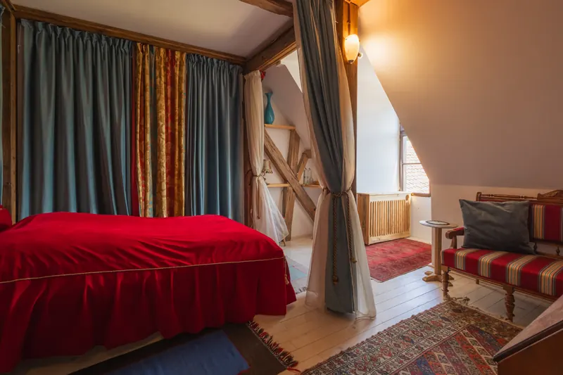 The Honeymoon Room inside Miklósvár Castle, with a red-covered bed framed by curtains