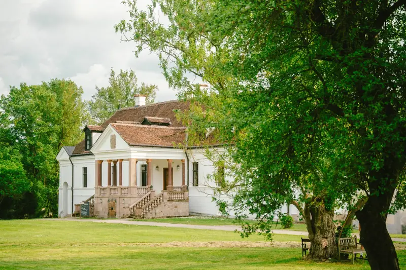 Kálnoky Castle in Miklósvár, framed by trees and its green garden
